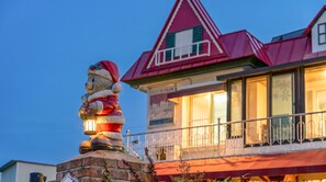 Um edifício com telhado vermelho e uma estátua de um urso segurando um candeeiro.