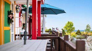En træterrasse med en blå parasol, gelænder og havudsigt.