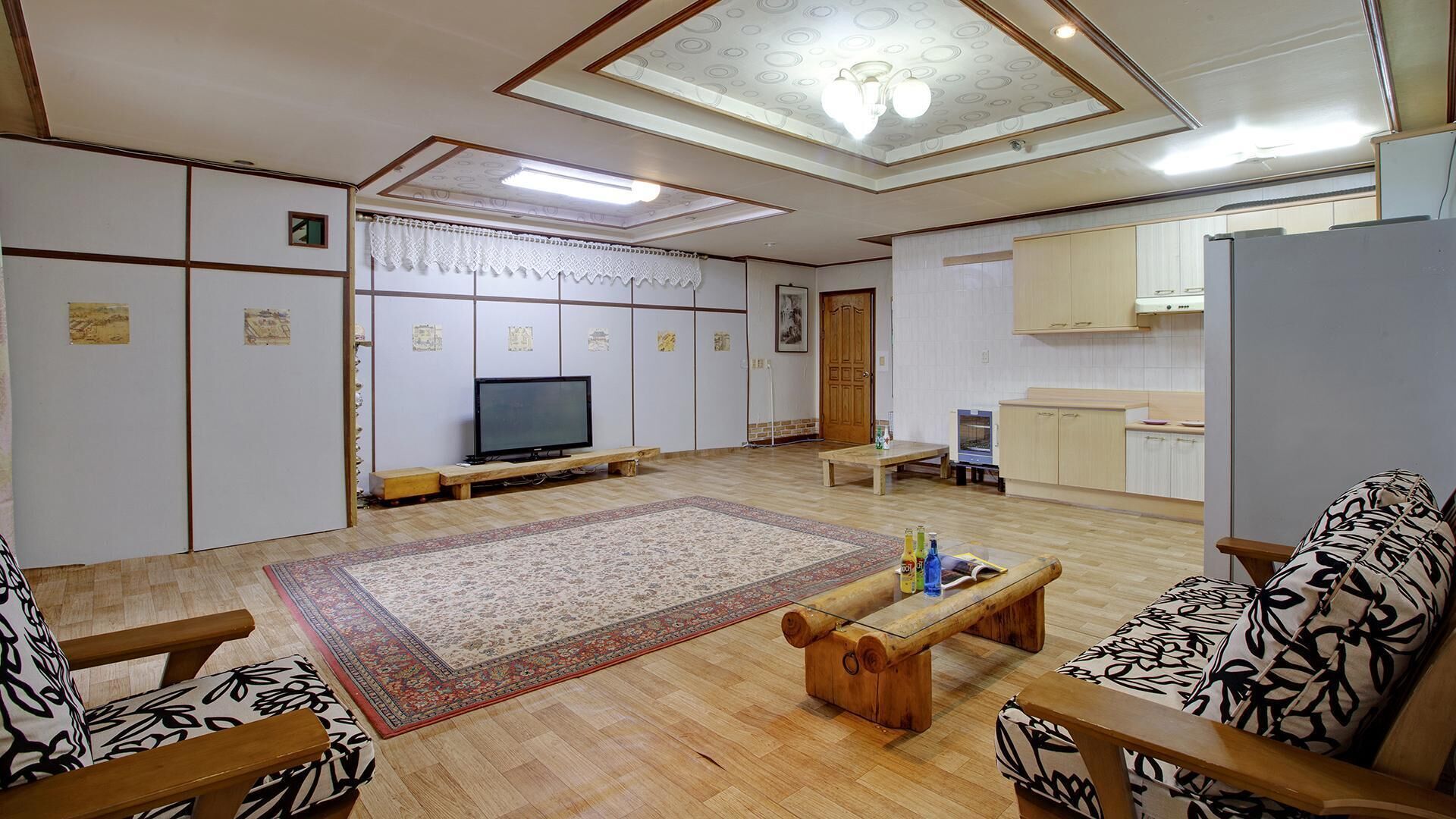 A spacious living room with a television, a wooden coffee table, and patterned sofas.