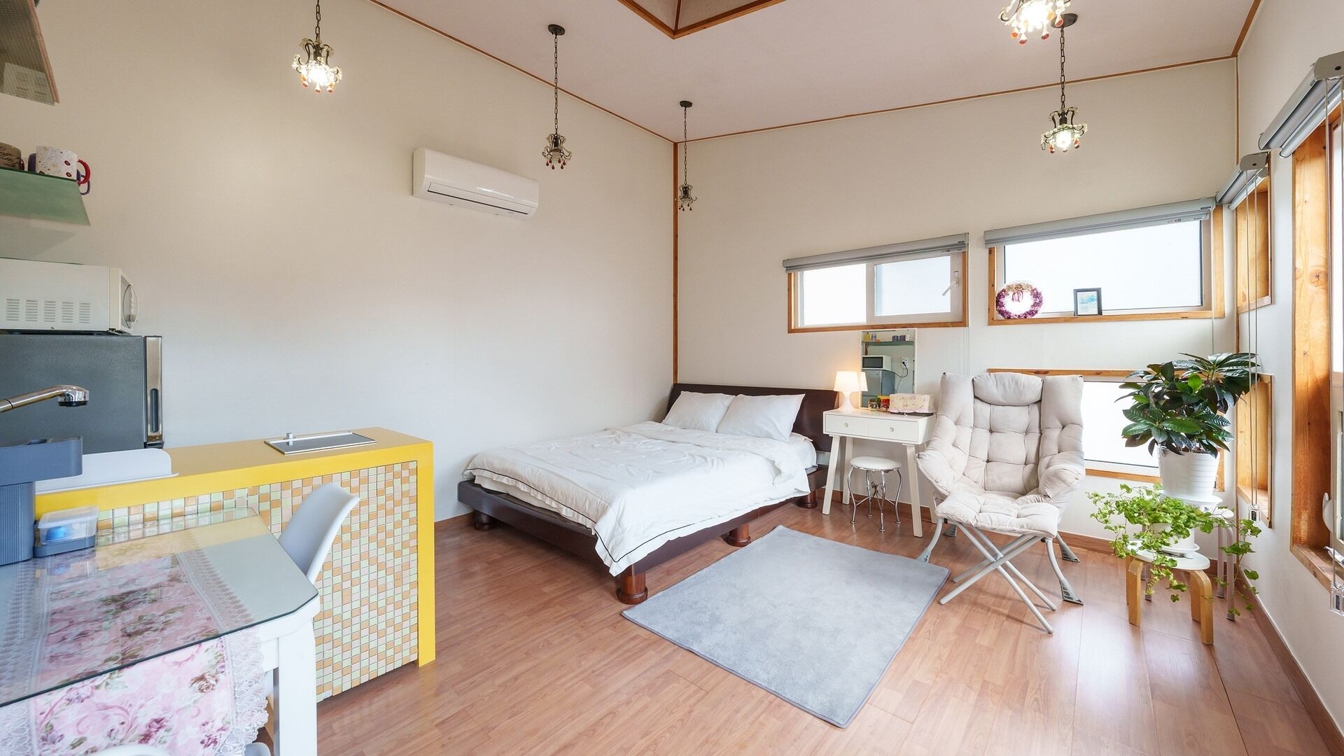 Une chambre à coucher comprenant un lit, une table de chevet, une chaise, un bureau et des plantes en pot.