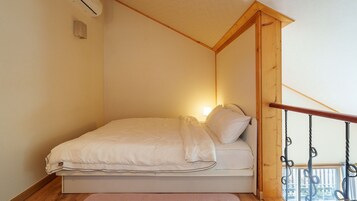 Una cama individual en una habitación con techo inclinado y barandilla de madera.