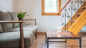 A living room with a sofa, a coffee table, a potted plant, and a staircase with a wrought iron railing. - Hongcheon Lime Orange Pension (Hongcheon)