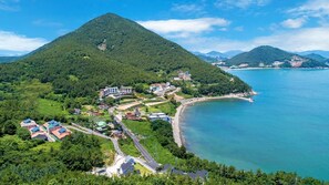 Vista aérea de una zona costera con una montaña destacada, una playa y varios edificios con paneles solares.