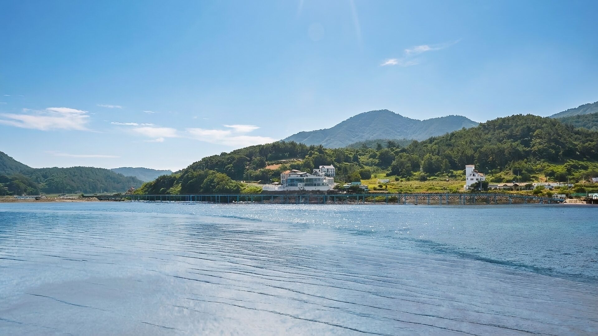 A waterfront property with a view of a mountain range, a bridge, and a body of water.