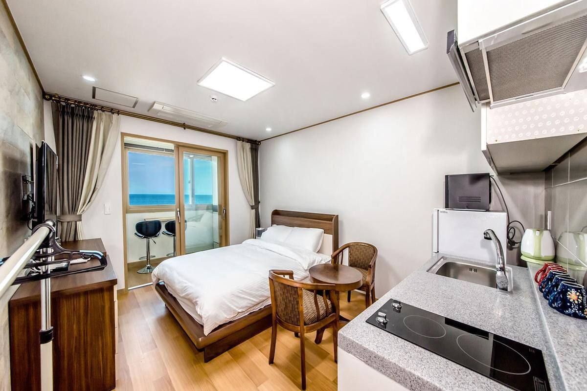 Ein Hotelzimmer mit Bett, einer kleinen Essecke, einer Küchenzeile und Meerblick.