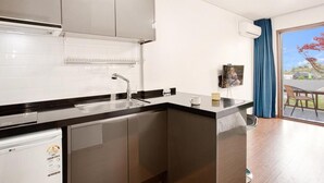 A compact kitchen with a built-in dishwasher, a sink, and a small countertop. - Jeju Kiaora Resort (Seogwipo)