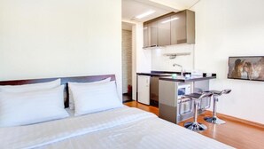 A hotel room with a bed, a kitchenette, and a small bar area. - Jeju Kiaora Resort (Seogwipo)