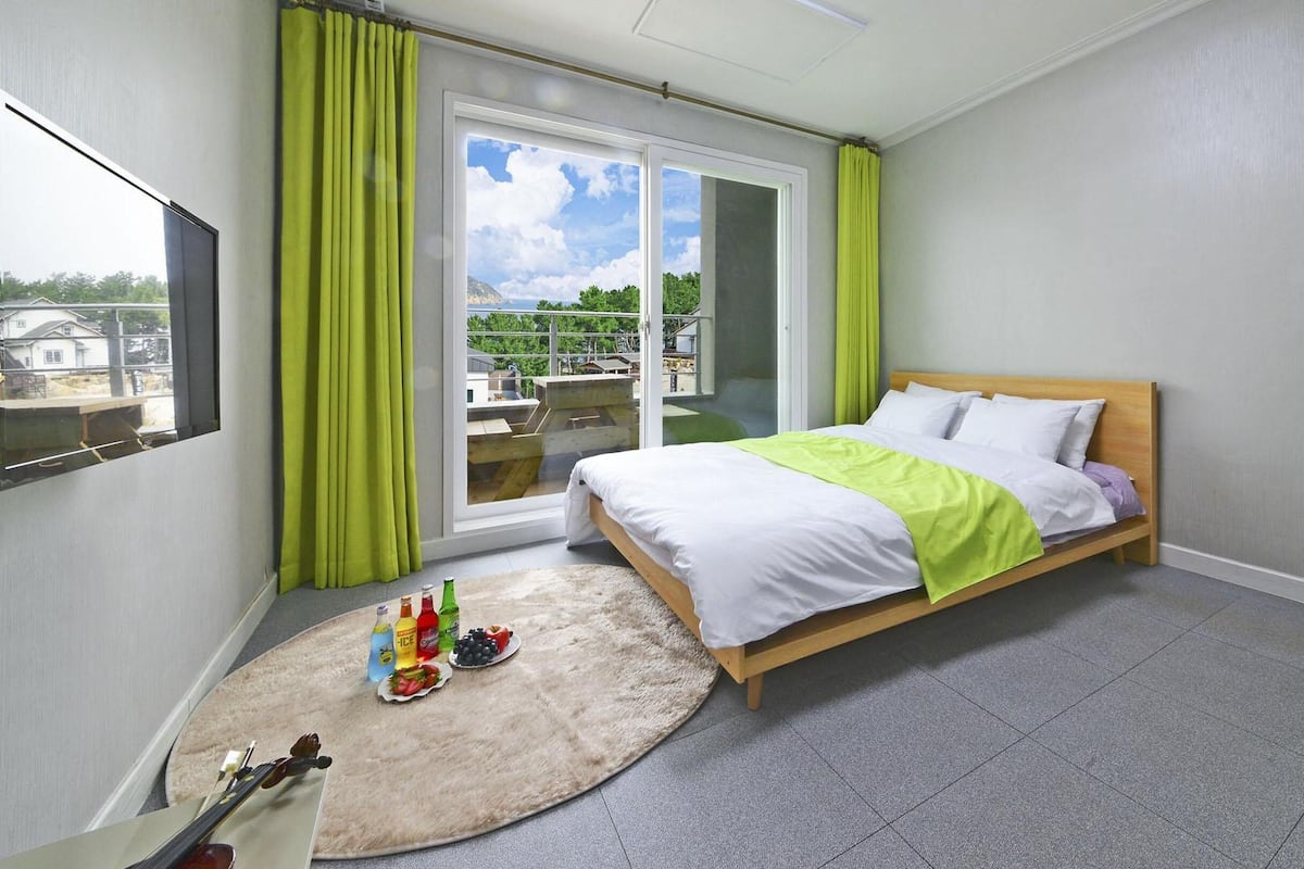 Une chambre à coucher avec un lit, un tapis rond et une fenêtre avec des rideaux.