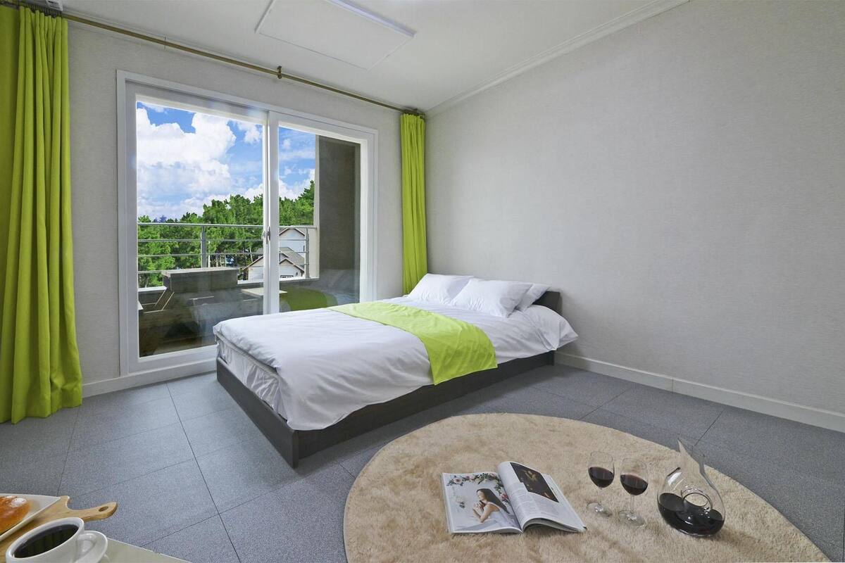 Une chambre d’hôtel avec un lit, une petite table ronde sur laquelle se trouvent un magazine, des verres et un verre à vin.