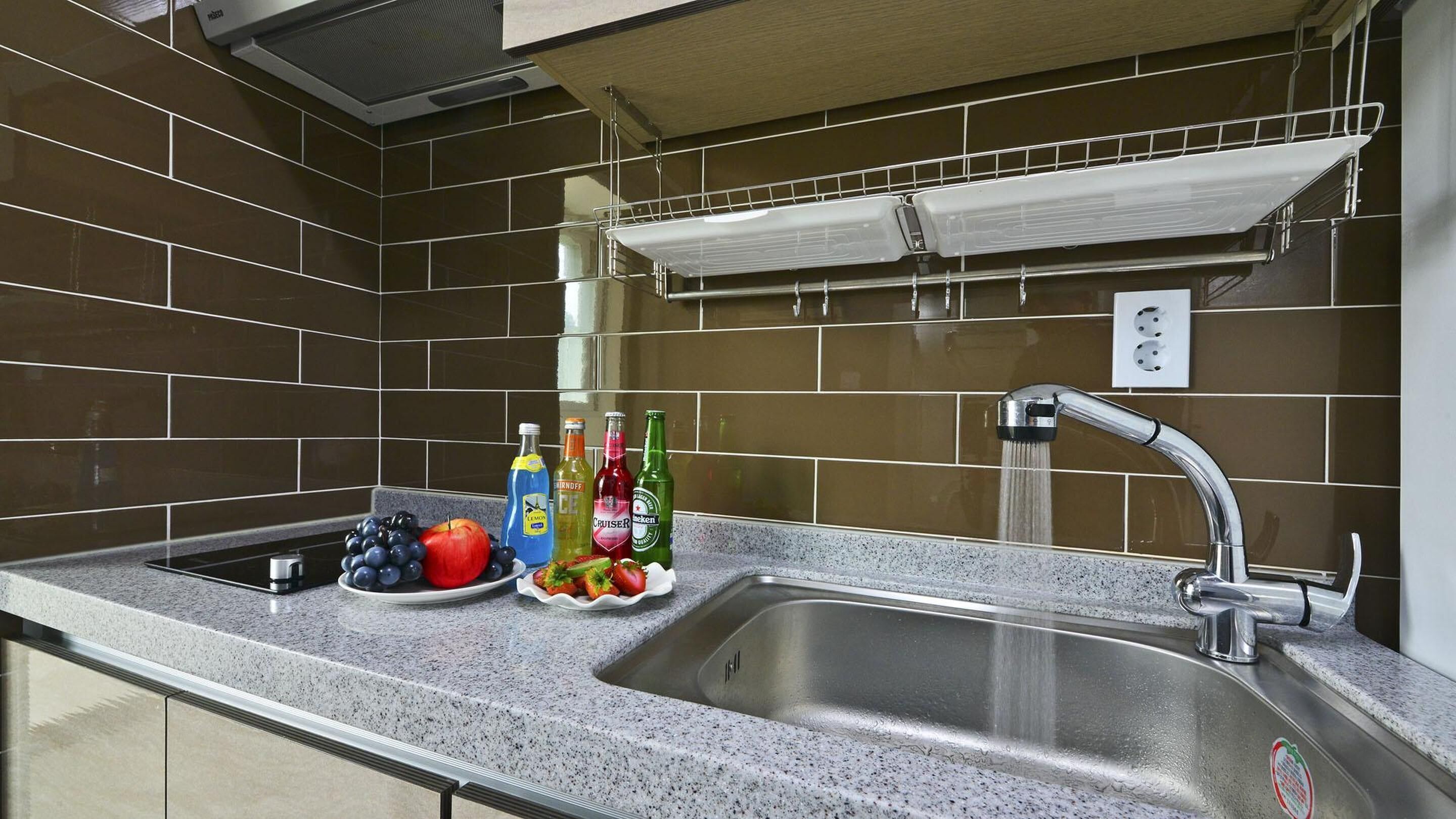 Een keuken met een granieten aanrecht, een roestvrijstalen spoelbak en een hangrek erboven.