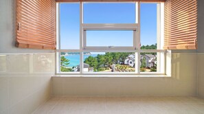 A room with a large window overlooking a residential area and a body of water. - Janghohang J Story Pension (Samcheok)