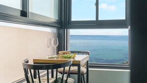 Uma mesa de jantar com duas taças de vinho e um buquê de flores, com vista para o mar.