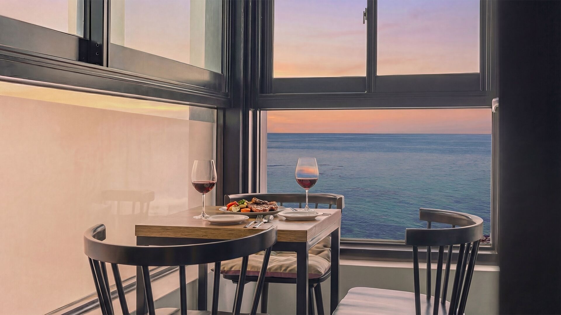 A dining table with chairs, a glass of red wine, and a plate of food.