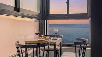 A dining table with chairs, a glass of red wine, and a plate of food.