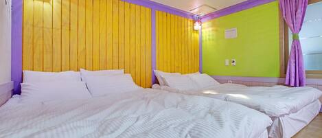 A hotel room with two beds, yellow and purple walls, and a green accent wall.