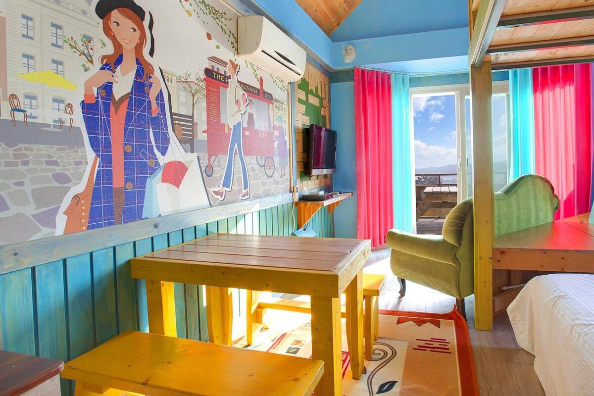 A room with bunk beds, a mural, a table, and a chair.