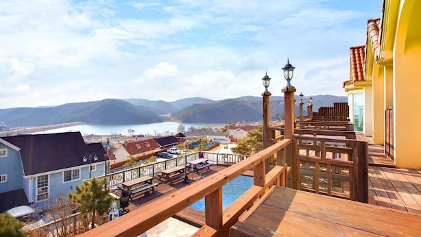 Eine Holzterrasse mit Picknicktischen mit Blick auf einen See und Berge.