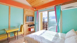 Ein Hotelzimmer mit Bett, Schreibtisch mit Stuhl, Fernseher und Blick auf die Stadt durch das Fenster.