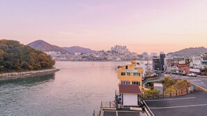 Un paysage urbain côtier avec une rivière paisible, un mélange de bâtiments résidentiels et commerciaux, et un bâtiment jaune imposant avec une enseigne.