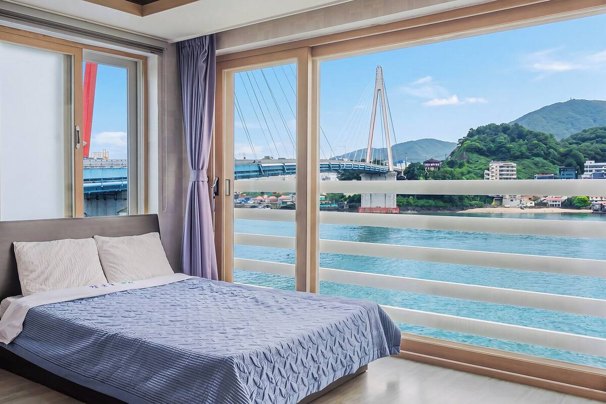 Une chambre d’hôtel avec un grand lit, une vue sur un pont et une montagne en arrière-plan.