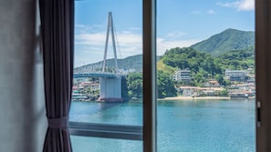 Blick auf eine Brücke über Wasser, im Hintergrund Gebäude und Hügel.