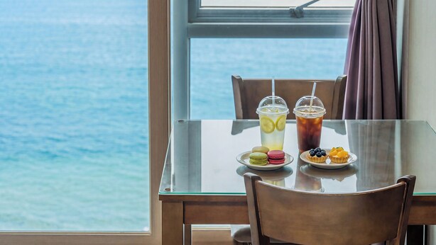 Une table avec deux boissons, une assiette de macarons et une assiette de fruits.