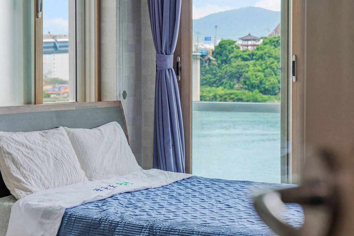 Une chambre d’hôtel avec un lit, une vue sur un plan d’eau et une montagne en arrière-plan.