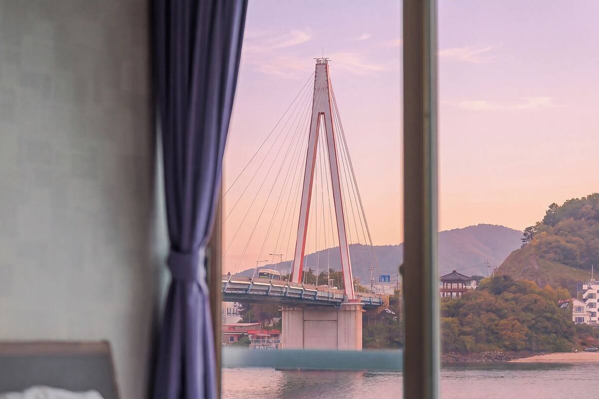 Une chambre avec vue sur un pont, une fenêtre avec des rideaux et un lit.