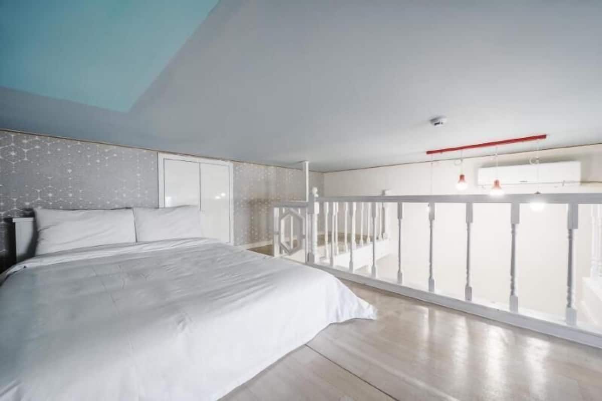 A bedroom with a bed, a balcony, and a view of the sky.