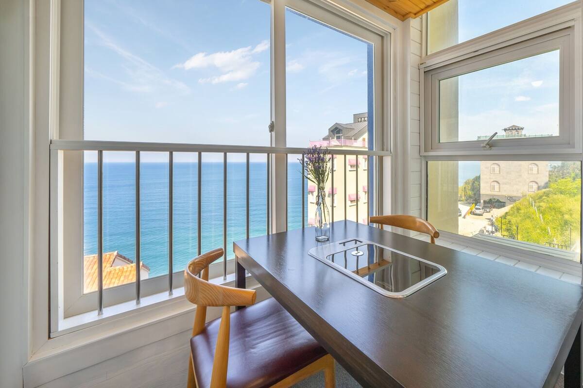 A balcony with a view of the sea and a building across the water.