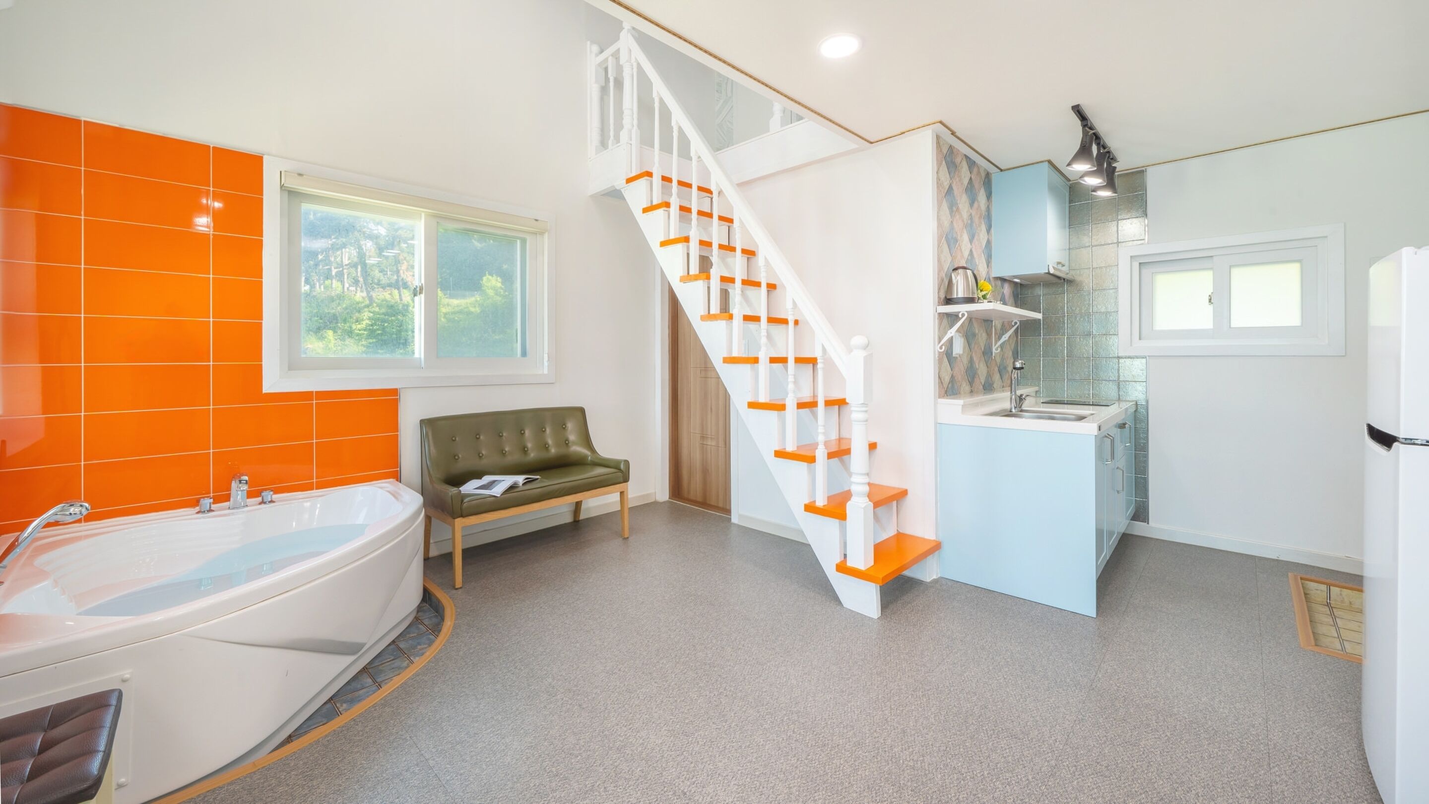 Ein Badezimmer mit einer Badewanne, einer grünen Bank und einer Treppe mit orangefarbenen Stufen.