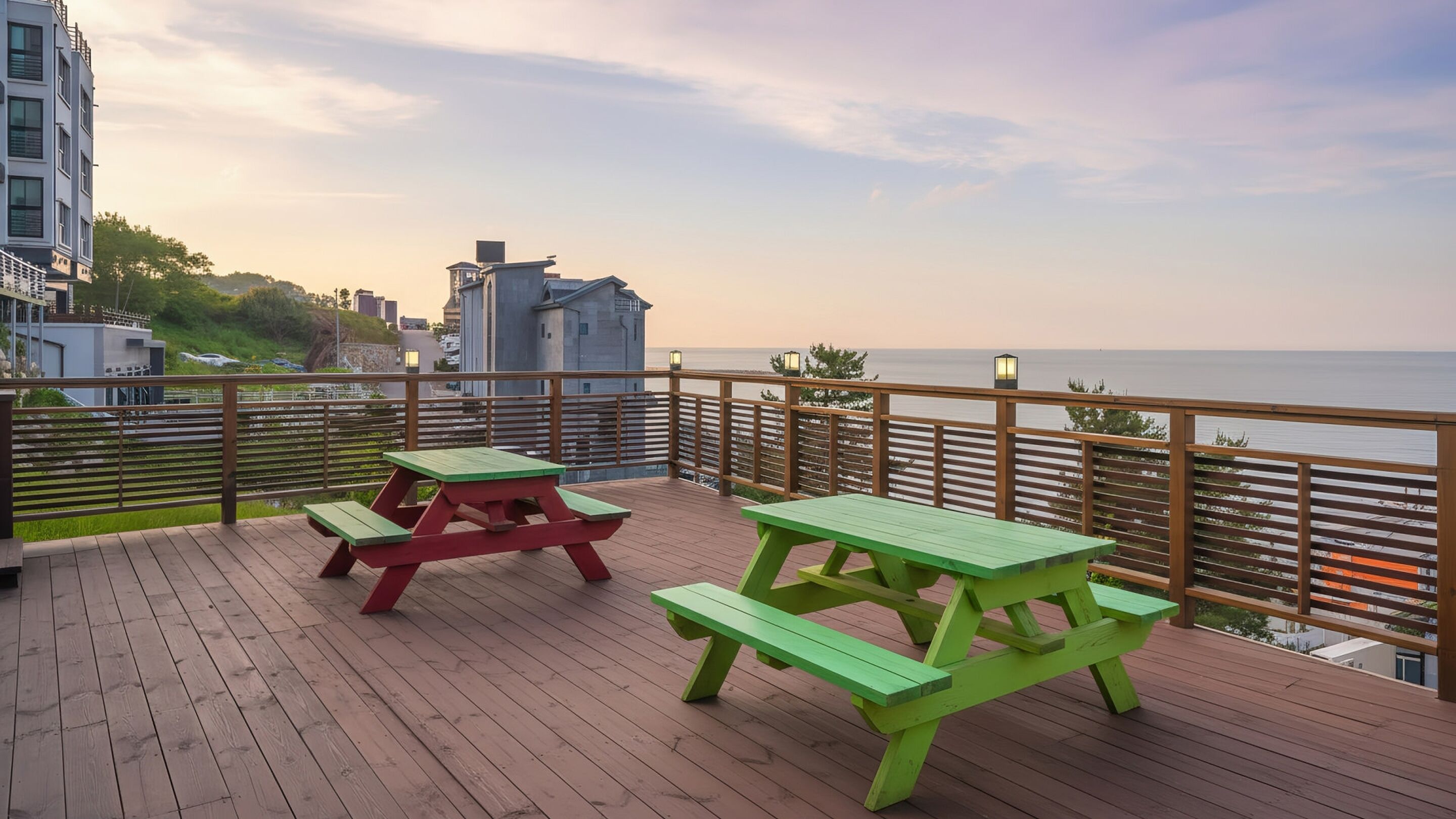 A wooden deck with picnic tables and a view of the sea.