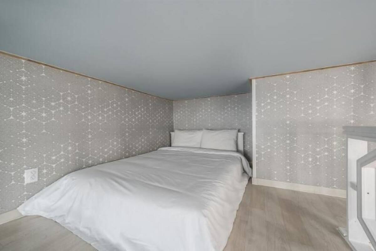 A bedroom with a bed, a nightstand, and a wall with a hexagonal pattern.