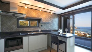 A modern kitchen with a large island, a built-in oven, and a view of the sea through large windows. - Donghae Haru Pension (Donghae)