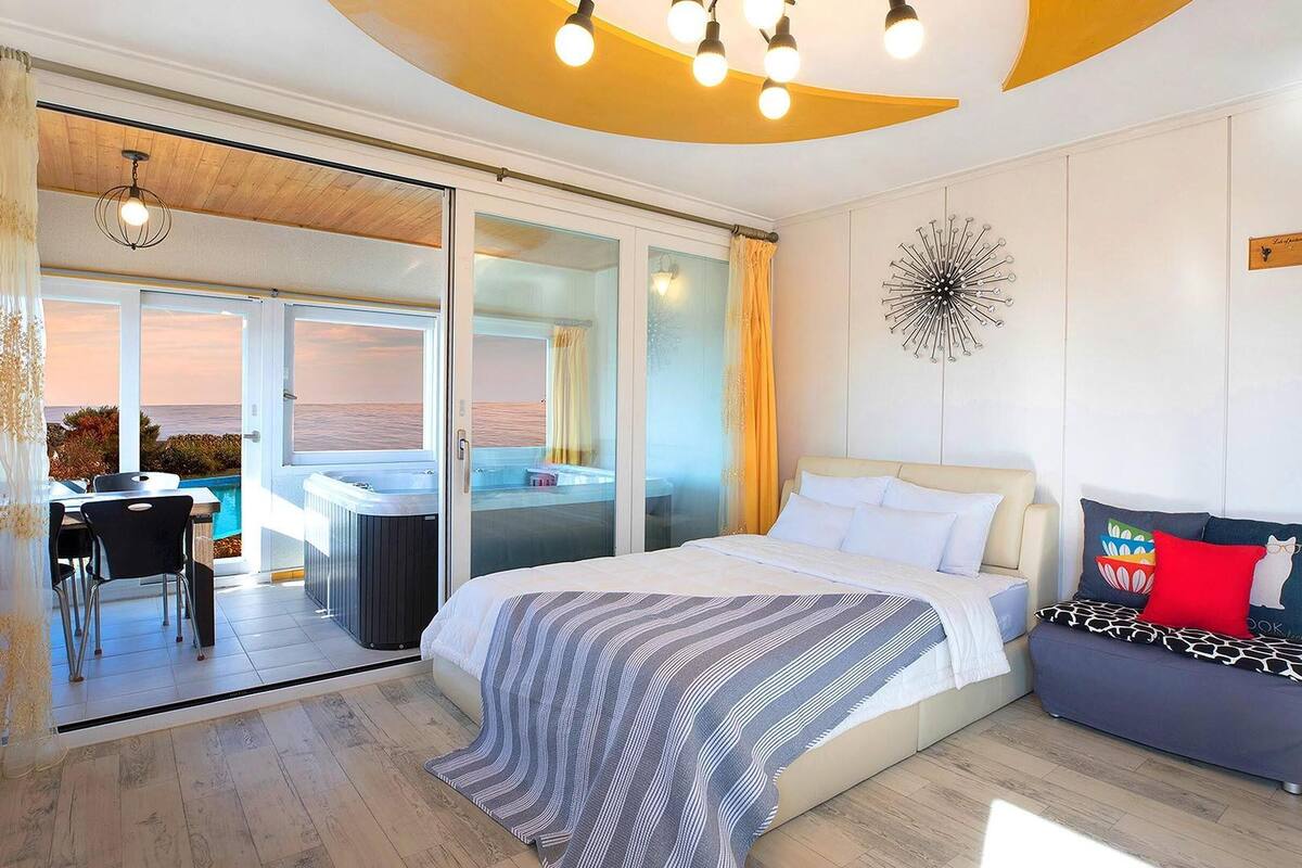 Une chambre avec un lit, un canapé, une vue sur la mer et un jacuzzi.