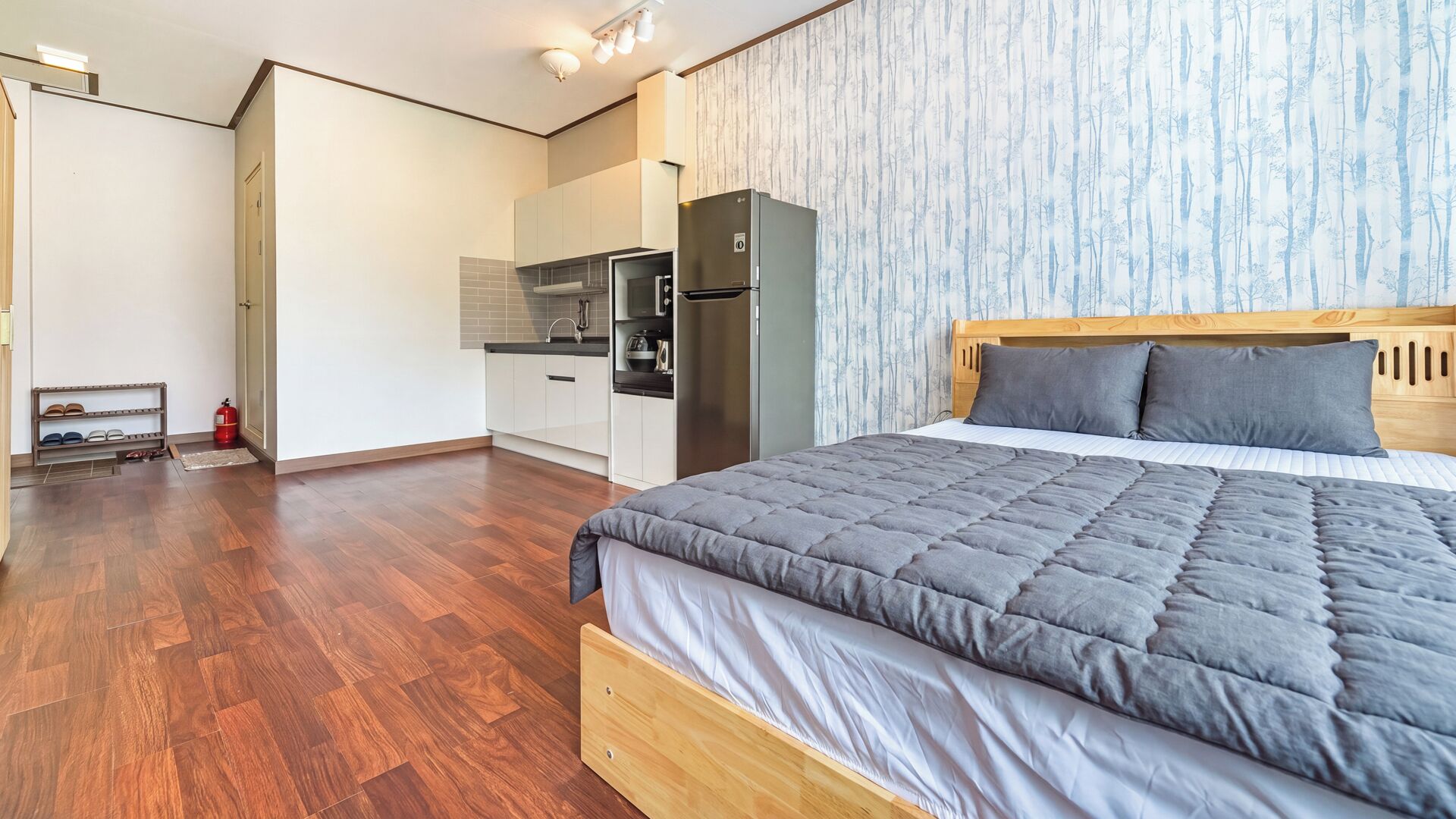 Une chambre à coucher moderne avec un grand lit, une tête de lit en bois et une couette grise.