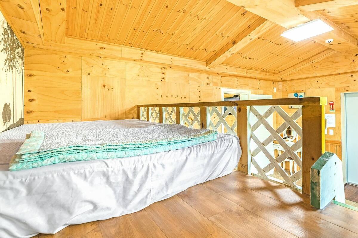 Ein Schlafzimmer einer Holzhütte mit Bett, Holzboden und einer Tür.