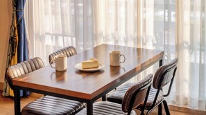 Une table à manger avec deux tasses et une part de gâteau au fromage, entourée de fauteuils en cuir.