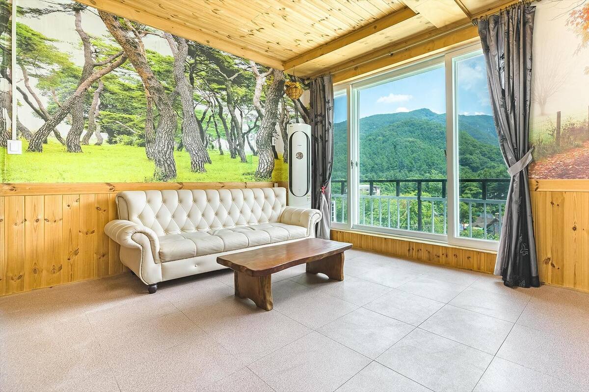 Ein Zimmer mit einem großen Fenster, einem weißen Sofa und einem Holztisch.