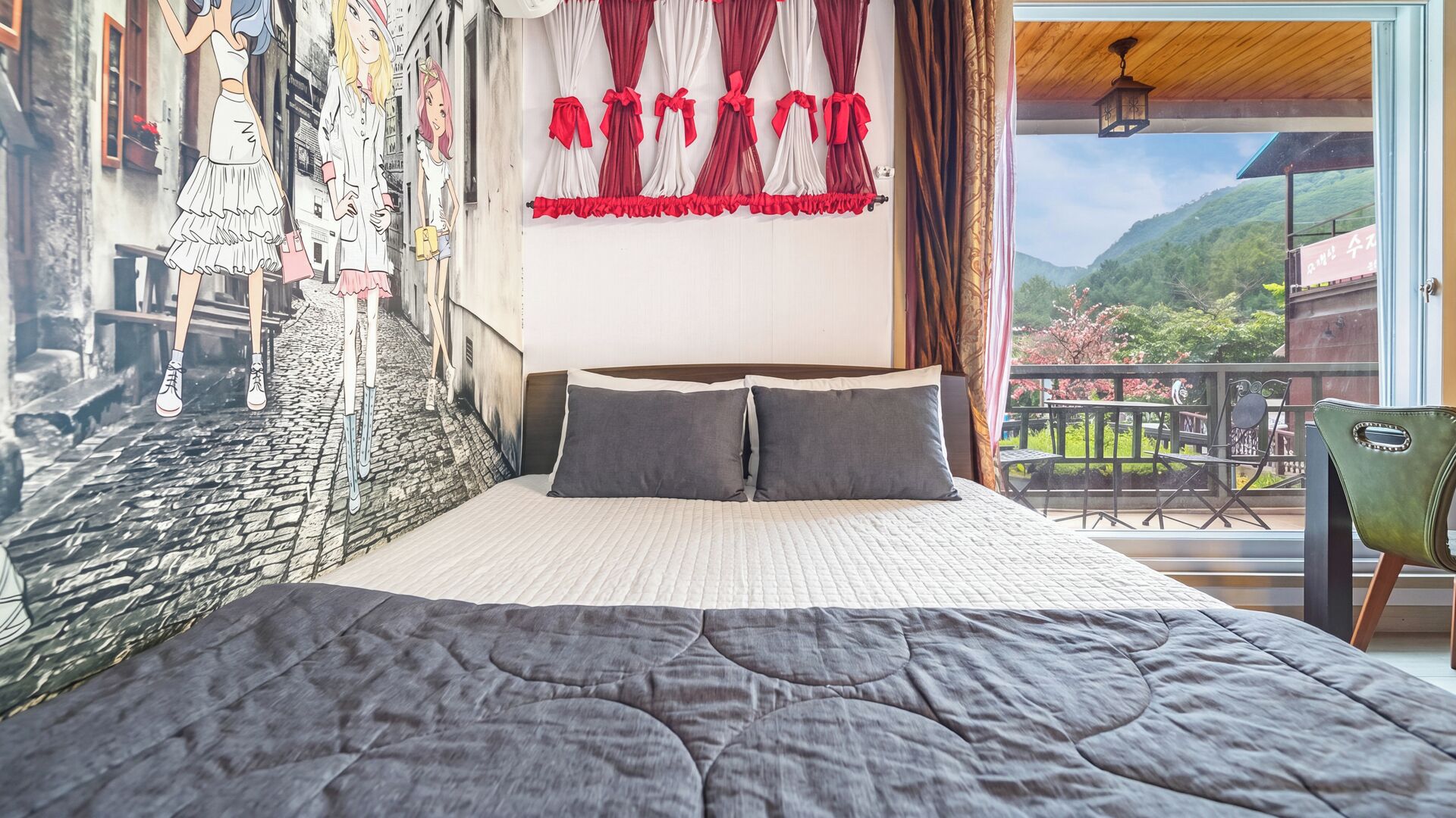 Ein Schlafzimmer mit einem großen Bett, Balkonblick und einem Wandbild.