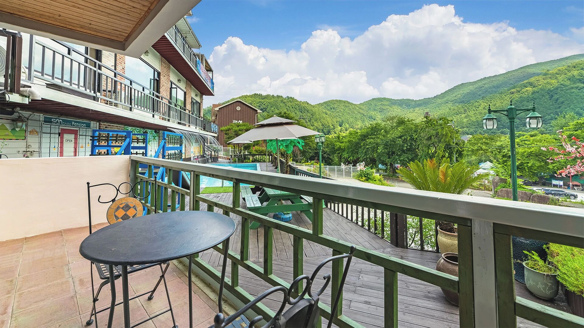 A balcony with a view of a mountain, a pool, and a restaurant.