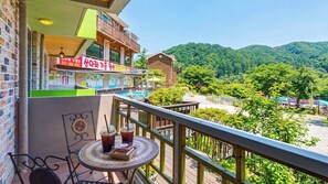 Un balcon avec une table de billard, deux boissons et une vue sur un paysage montagneux.