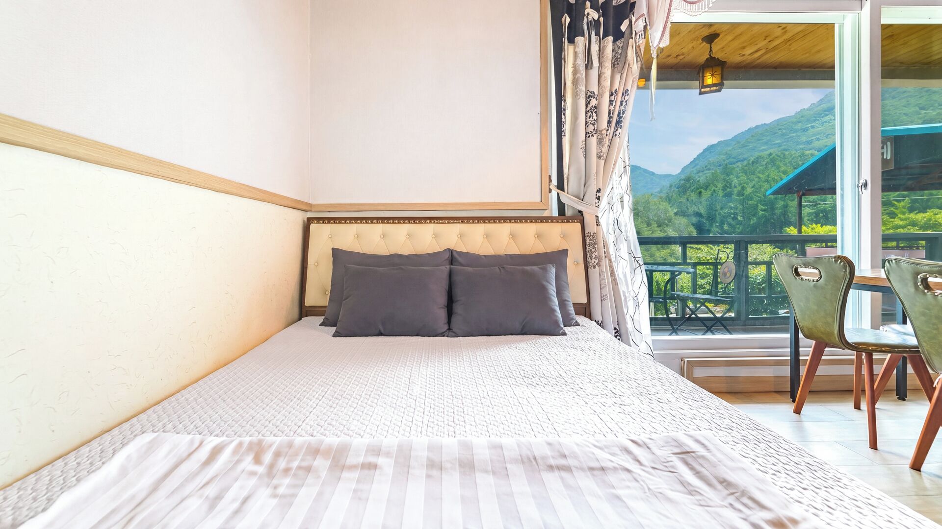Un dormitorio con cama, vistas al exterior y un balcón con sillas.