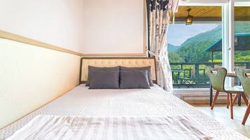 Un dormitorio con cama, vistas al exterior y un balcón con sillas.