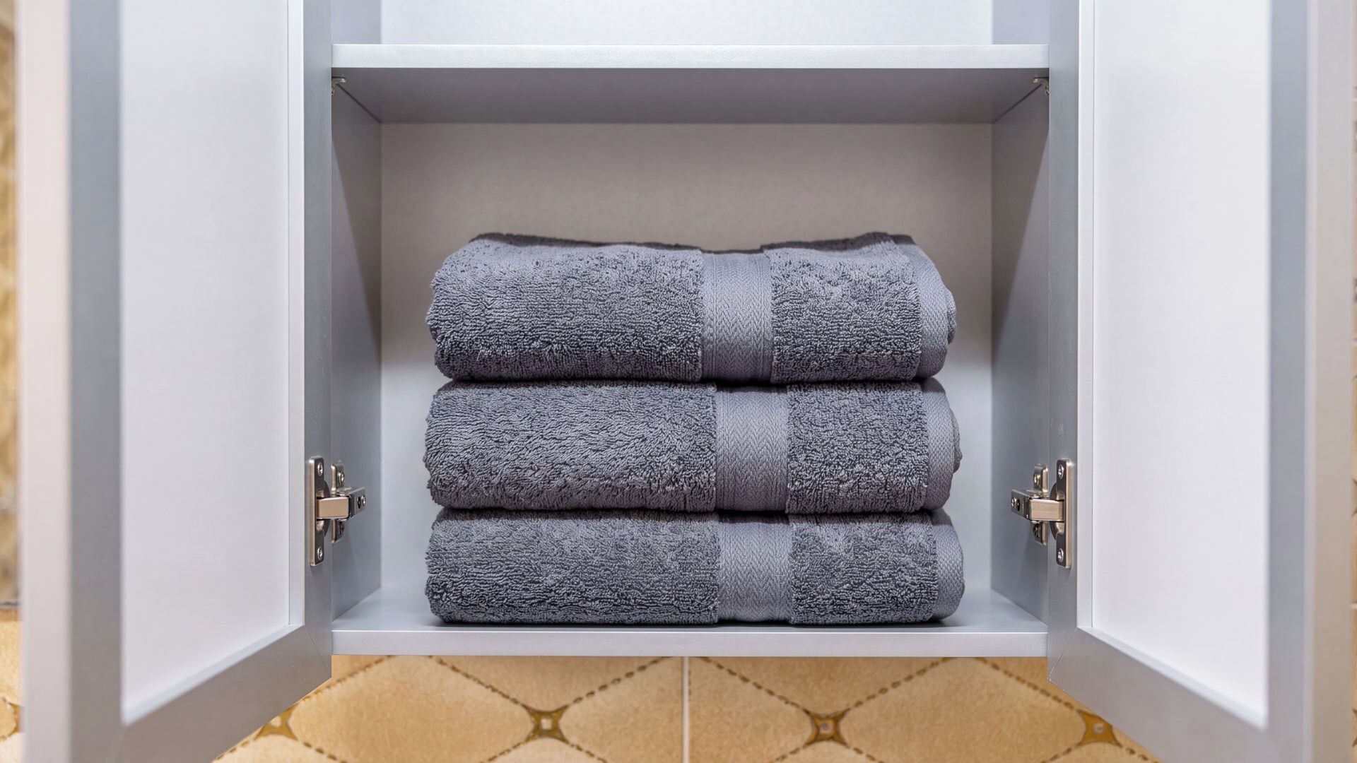 A white cabinet with a textured gray towel folded inside.