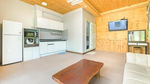 Un espace de vie compact comprenant un coin cuisine, un plafond en bois, une télévision et un canapé.