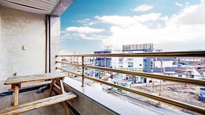 A balcony with a view of a cityscape, a wooden bench, and a railing. - Geoje Badasunjang Pension (Geoje)
