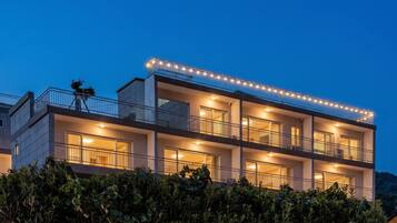 Un edificio de varios pisos con balcones, ventanas grandes y una fachada bien iluminada.