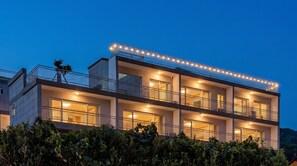 A multi-story building with balconies, large windows, and a well-lit facade.