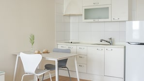 Una cocina compacta con armarios blancos, un microondas integrado y un lavamanos con un grifo moderno.
